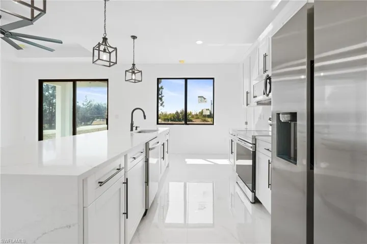 Kitchen with stainless steel appliances, a large island, a sink, and a healthy amount of sunlight