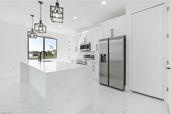 Kitchen with recessed lighting, a sink, white cabinets, marble finish floor, and appliances with stainless steel finishes