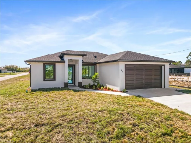 View of front facade with a garage, concrete driveway, roof with shingles, a front lawn, and stucco siding