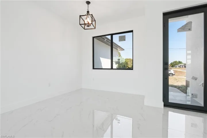 Spare room with a notable chandelier, marble finish floor, and baseboards