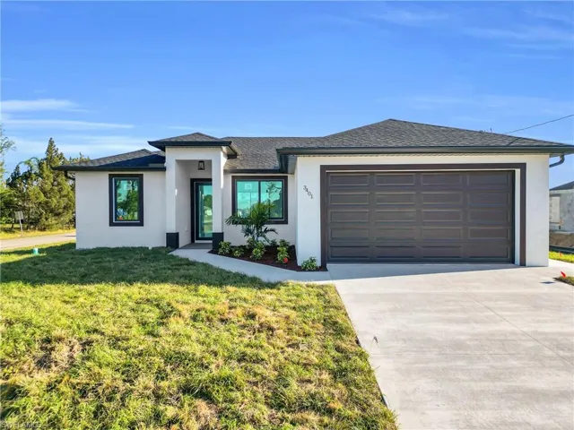 Prairie-style home with stucco siding, driveway, roof with shingles, an attached garage, and a front yard