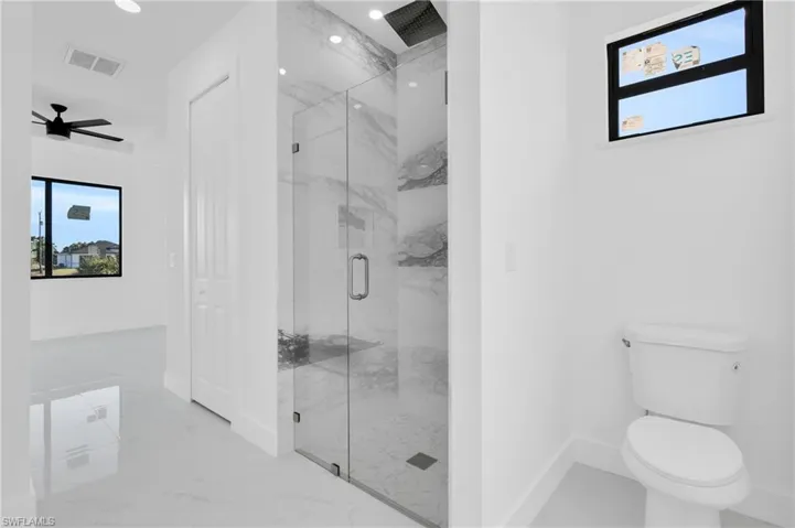 Full bathroom featuring a marble finish shower, visible vents, baseboards, toilet, and marble finish floor