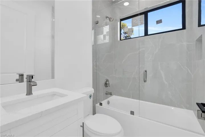 Bathroom with vanity, toilet, and bath / shower combo with glass door