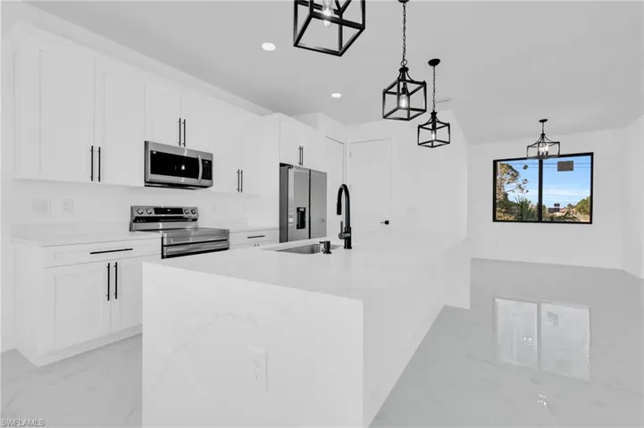 Kitchen featuring a sink, stainless steel appliances, marble finish floor, and white cabinetry