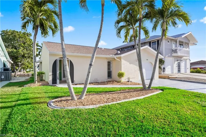 Charming curb appeal with a tropical landscape and welcoming entryway.