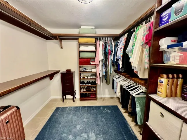 Primary walk in closet with custom built in shelving.