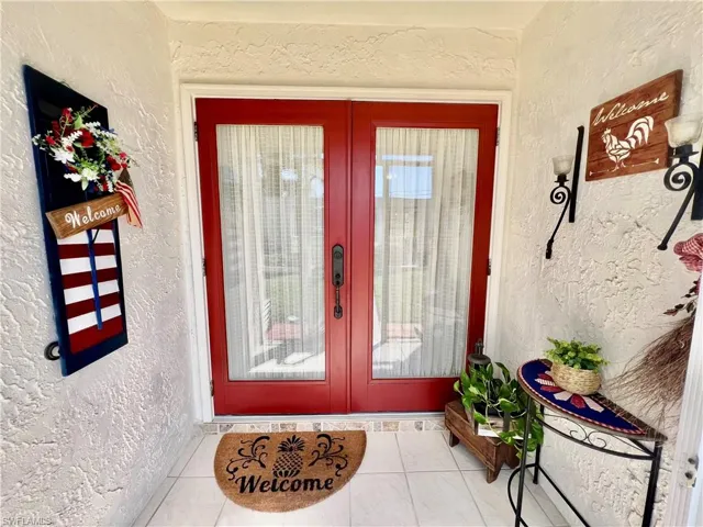 Screened front entryway with tile floors and  double doors to the home.