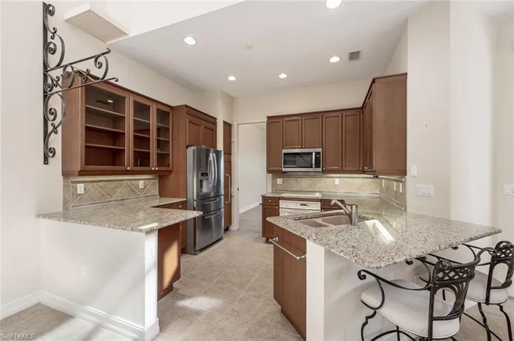 Kitchen featuring light stone countertops, kitchen peninsula, stainless steel appliances, and a breakfast bar area