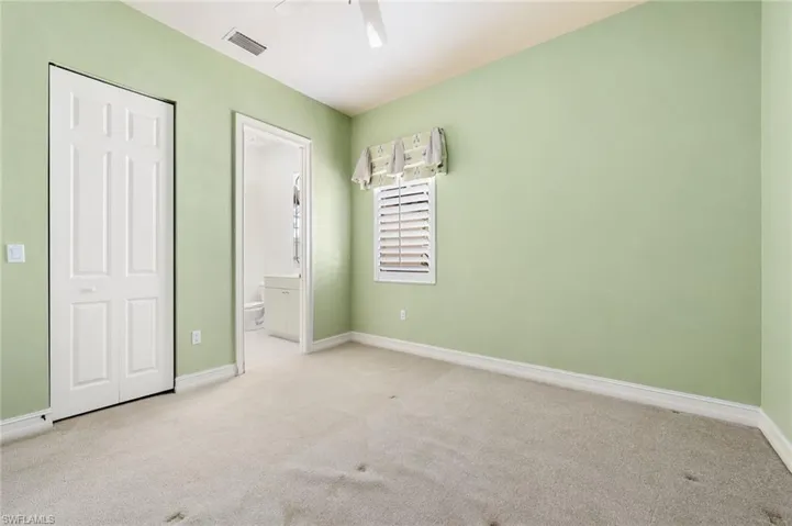 Unfurnished bedroom featuring ensuite bathroom, ceiling fan, and light carpet