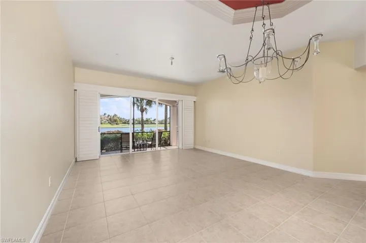 Spare room featuring light tile patterned flooring, ornamental molding, and a chandelier