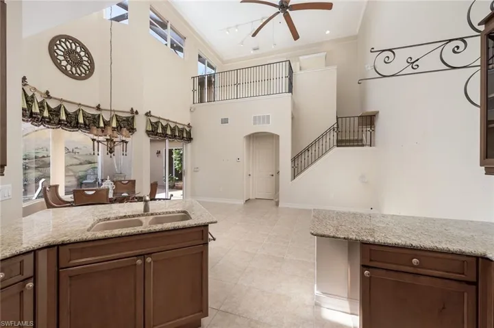 Kitchen with plenty of natural light, light stone countertops, sink, and a high ceiling