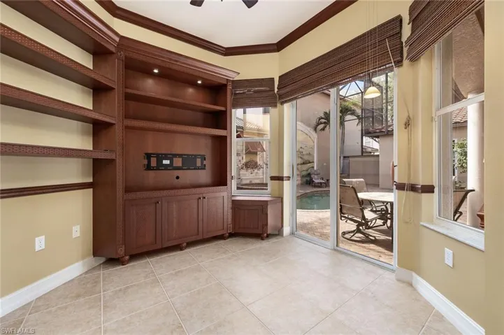 Unfurnished office with ceiling fan, light tile patterned floors, and crown molding