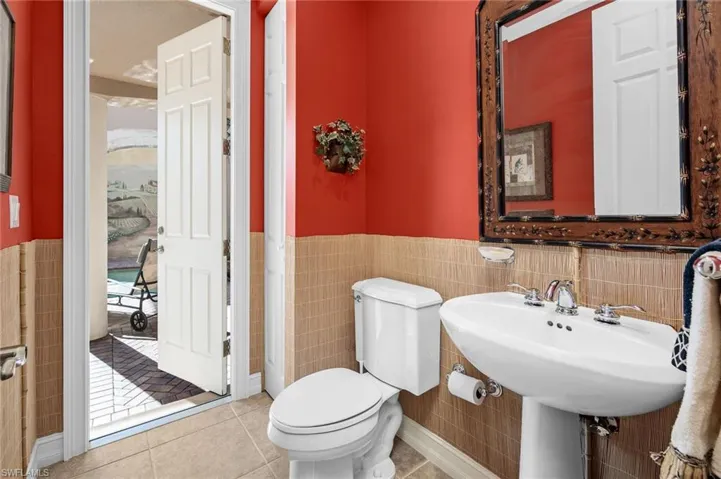 Bathroom with toilet, tile patterned floors, and tile walls