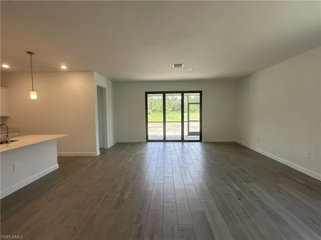 Unfurnished living room featuring sink and dark hardwood / wood-style floors