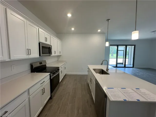 Kitchen featuring white cabinetry, stainless steel appliances, pendant lighting, sink, and dark wood-type flooring