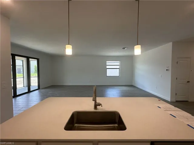 Kitchen featuring sink, an island with sink, a healthy amount of sunlight, and decorative light fixtures