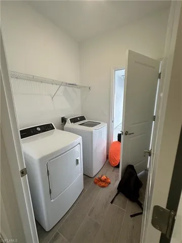 Clothes washing area featuring hardwood / wood-style flooring and washer and dryer