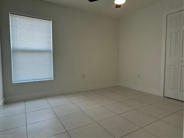 Spare room with a ceiling fan, light tile patterned floors, and baseboards