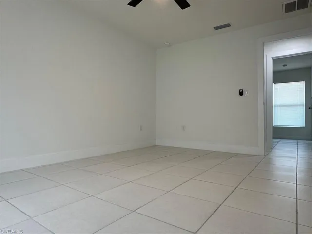 Unfurnished room with a ceiling fan, light tile patterned flooring, and baseboards