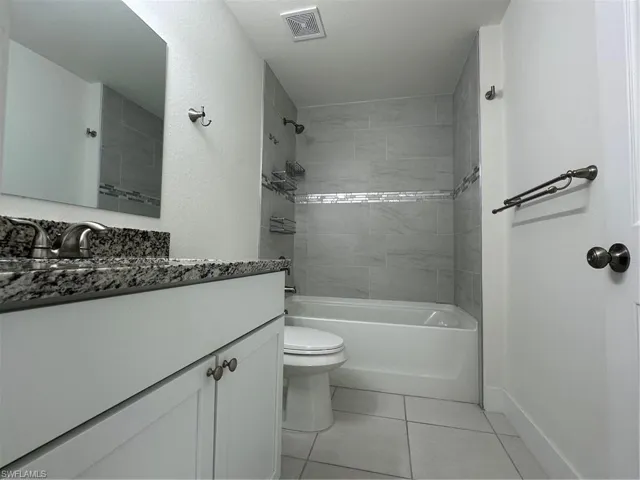 Bathroom featuring toilet, tile patterned flooring, vanity, and shower / bathtub combination