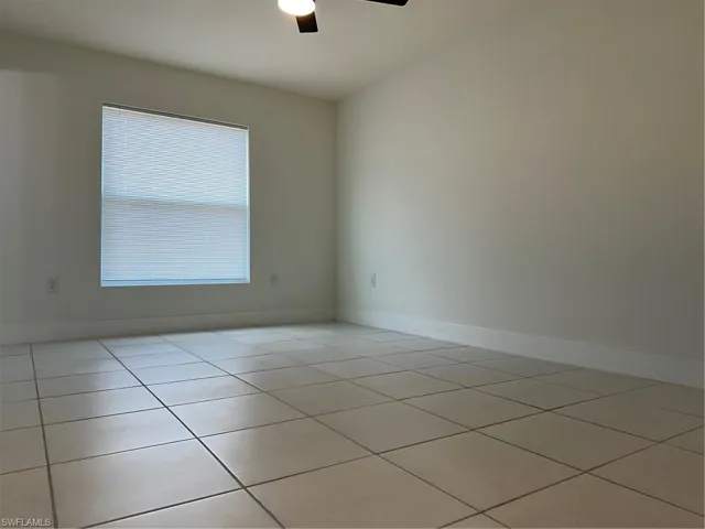 Unfurnished room featuring ceiling fan, light tile patterned flooring, and baseboards
