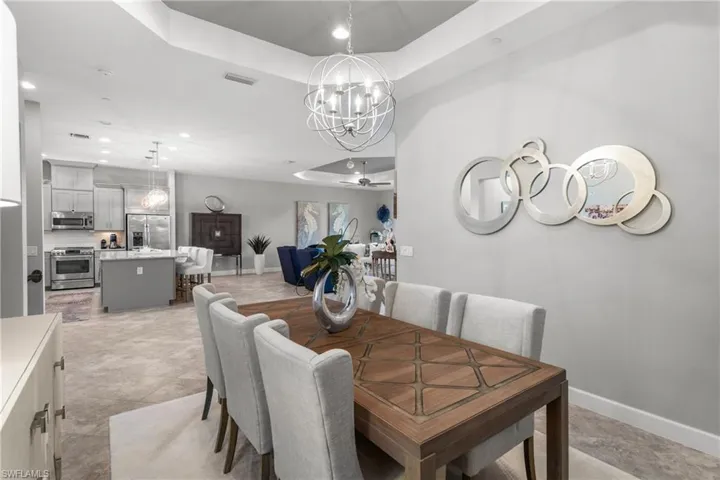 Dining room with a chandelier, a tray ceiling, baseboards, and recessed lighting