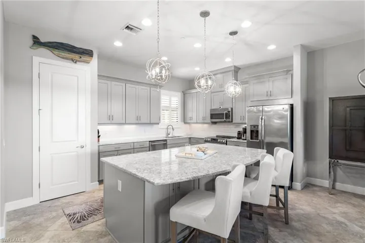 Kitchen with stainless steel appliances, a kitchen island, recessed lighting, tasteful backsplash, and a sink