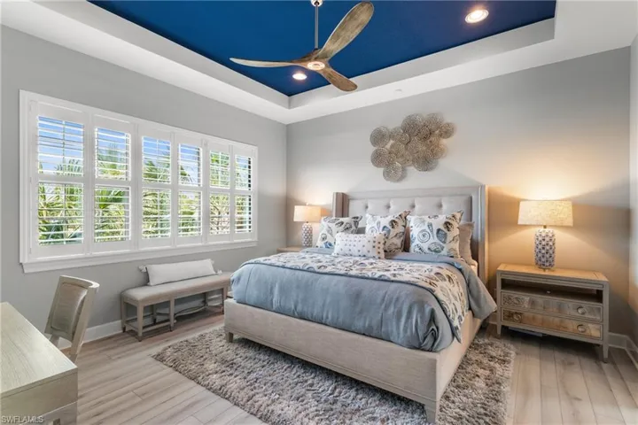 Bedroom featuring a raised ceiling, wood finished floors, baseboards, a ceiling fan, and recessed lighting