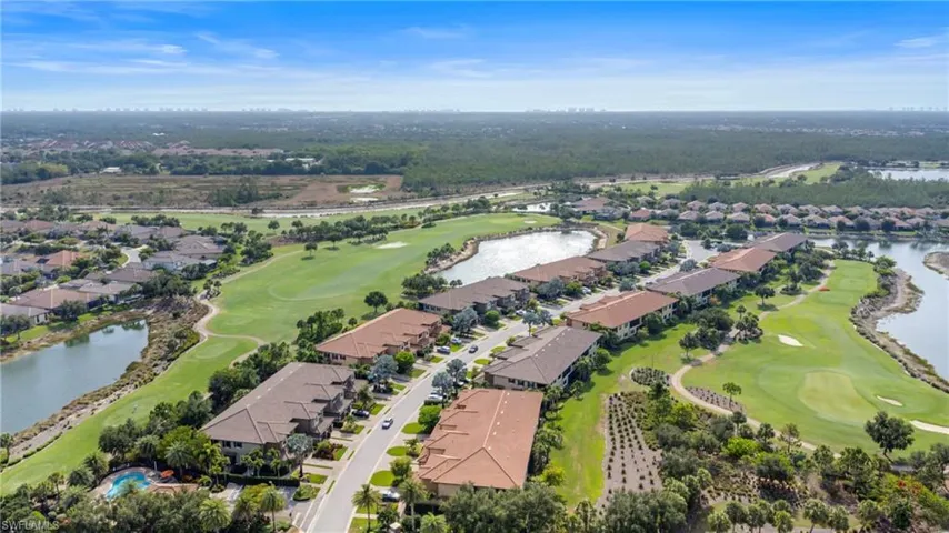 Aerial view of property and surrounding area with nearby suburban area, a local golf course, and a large body of water