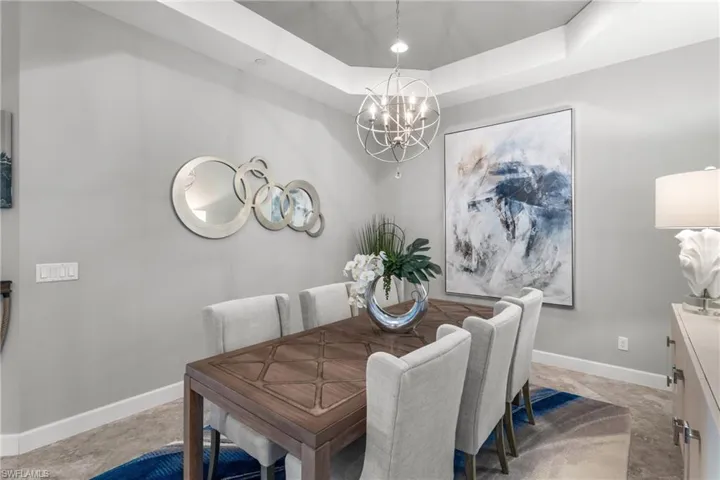 Dining room with a chandelier, baseboards, and a tray ceiling