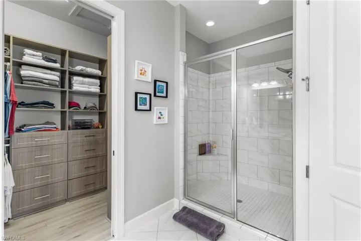 Full bathroom with baseboards, a shower stall, marble look tile flooring, recessed lighting, and a walk in closet