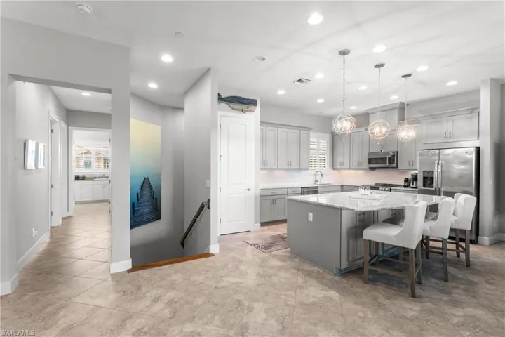 Kitchen with stainless steel appliances, a kitchen island, baseboards, recessed lighting, and light stone counters
