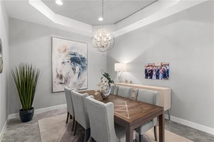 Dining space featuring a chandelier, baseboards, a raised ceiling, and recessed lighting