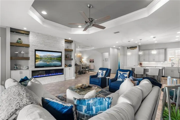 Living area featuring built in features, ornamental molding, a tray ceiling, recessed lighting, and ceiling fan