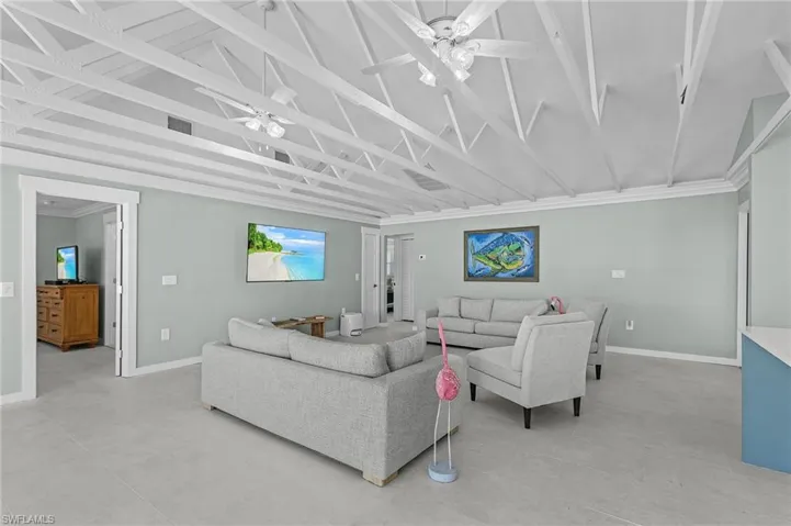 Living room with vaulted ceiling, ceiling fan, and crown molding