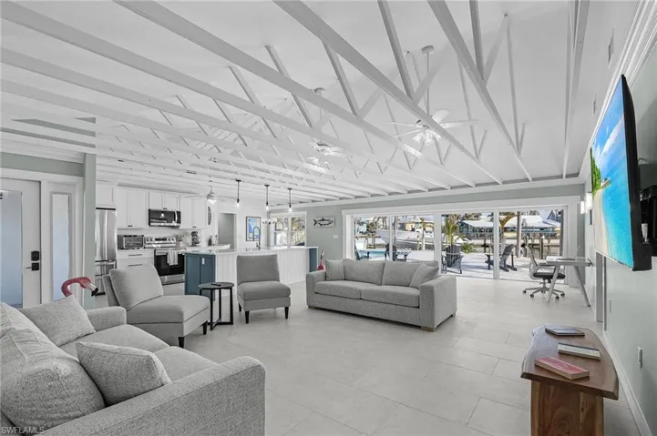 Living room featuring a wealth of natural light, ceiling fan, and lofted ceiling with beams