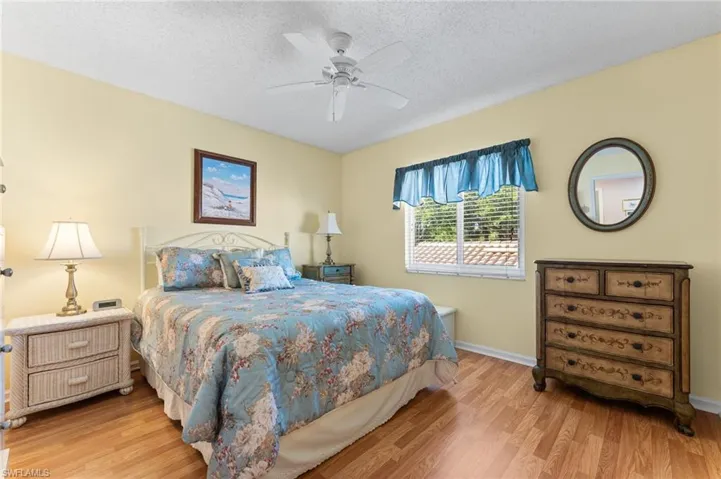 Bedroom with ceiling fan, baseboards, wood finished floors, and a textured ceiling