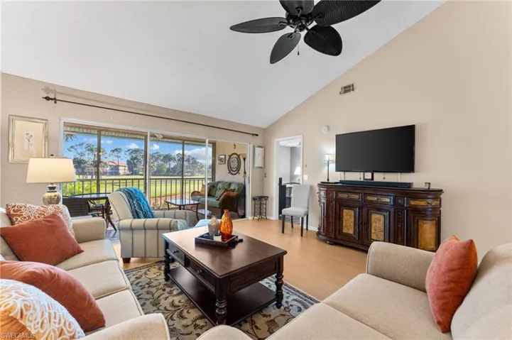 Living area with baseboards, visible vents, a ceiling fan, wood finished floors, and high vaulted ceiling