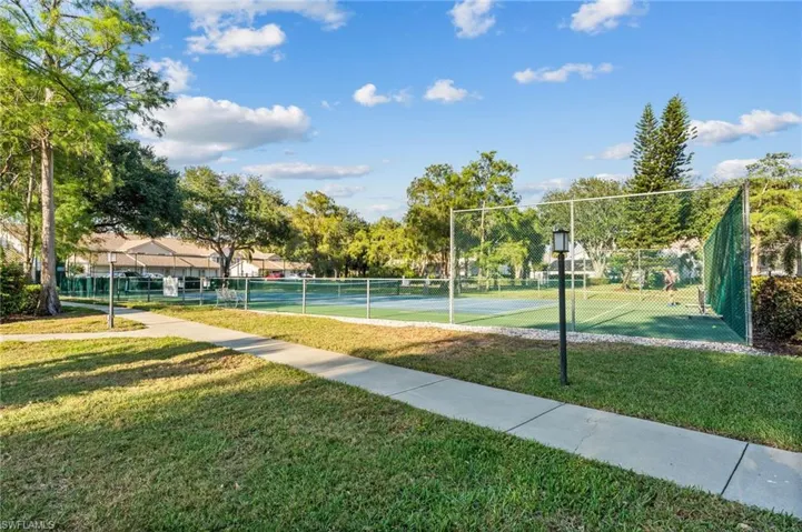 Surrounding community featuring fence, a lawn, and a tennis court