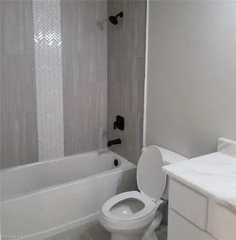 Full bathroom featuring tiled shower / bath, vanity, and toilet.  Cabinets will be gray in color.