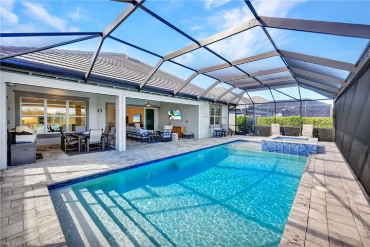 Integrated pool / spa with a sunroom, an outdoor living / dining area, glass enclosure, and a patio area