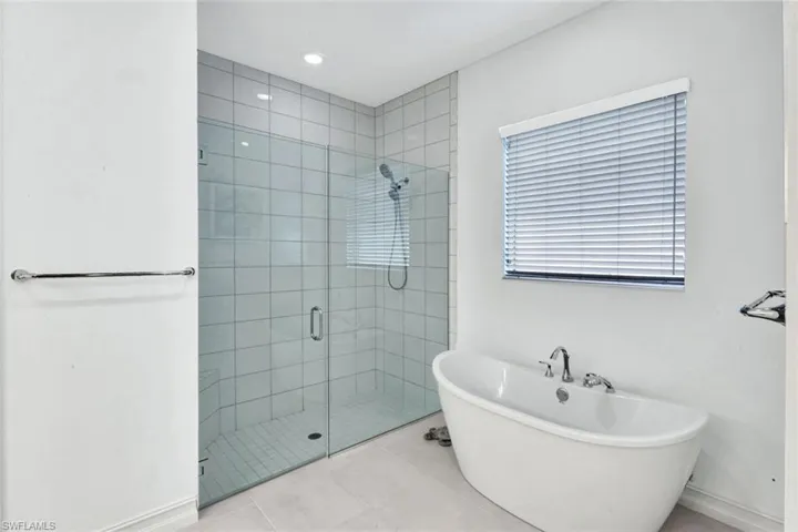 Bathroom featuring a shower stall, a freestanding tub, recessed lighting, and tile patterned flooring