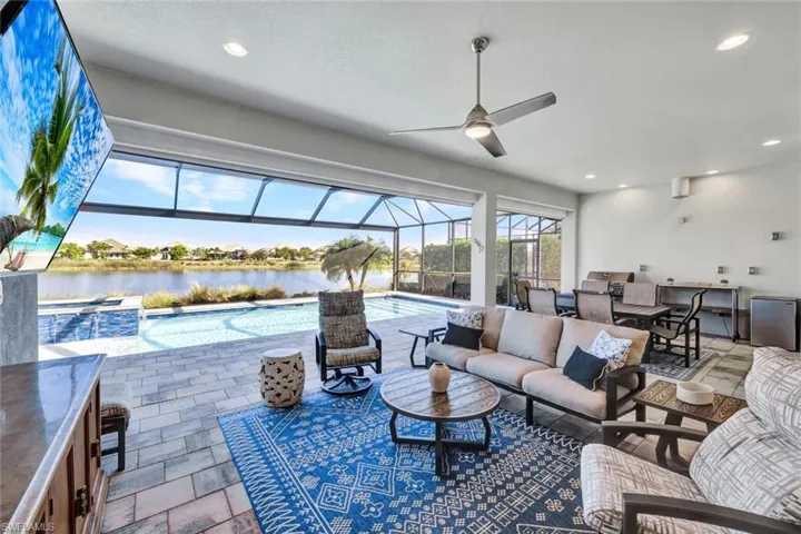 View of patio / terrace featuring glass enclosure, a sunroom, an outdoor kitchen, ceiling fan, and a pool with connected hot tub