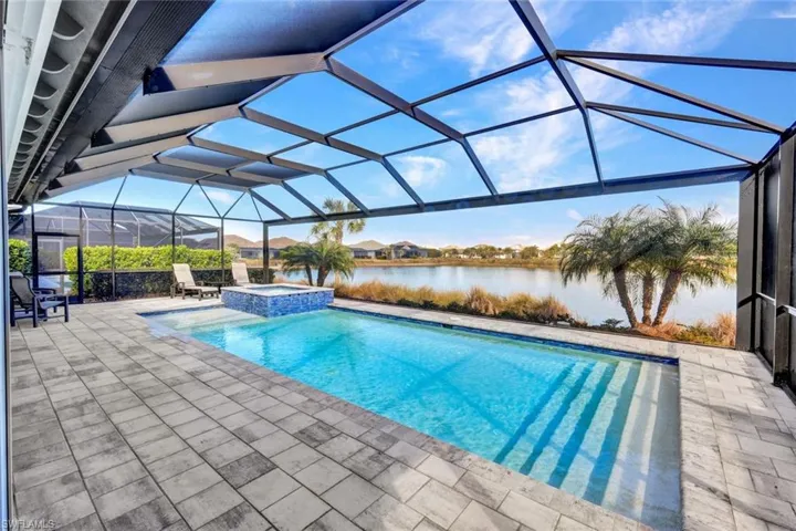 Integrated pool / hot tub with a sunroom, a patio area, a lanai, and a water view