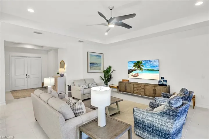Living area featuring light tile patterned floors, recessed lighting, a ceiling fan, and a raised ceiling