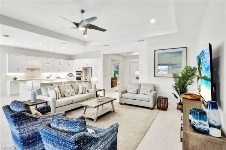 Living area with a ceiling fan, a raised ceiling, and recessed lighting
