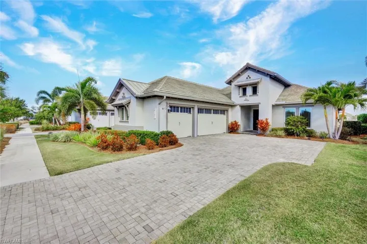 View of front of property with stucco siding, decorative driveway, a front yard, and a garage