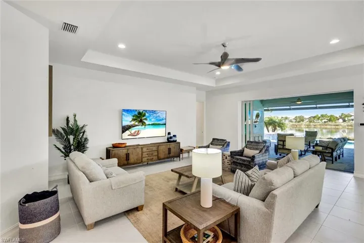 Living area with ceiling fan, a tray ceiling, a sunroom, recessed lighting, and light tile patterned floors