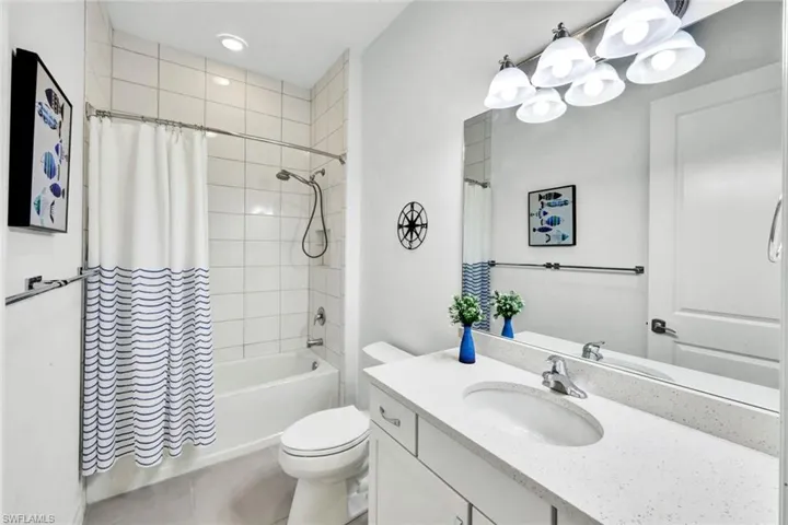 Full bath with shower / bath combo with shower curtain, vanity, light tile patterned flooring, and recessed lighting