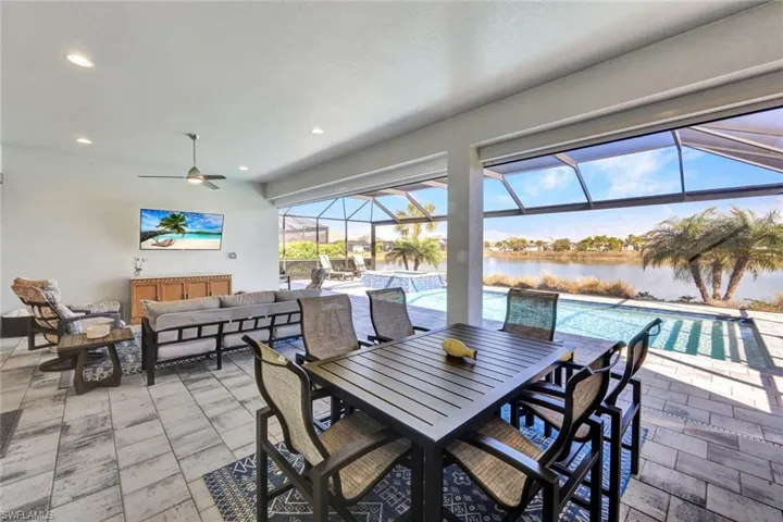 View of patio / terrace with a sunroom, an outdoor living / dining area, ceiling fan, a lanai, and a pool with connected hot tub